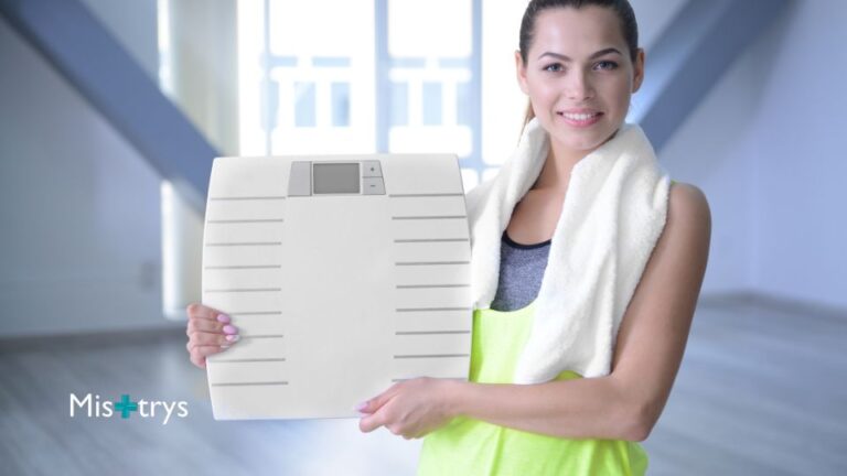Woman holding weighing scales in gym wear