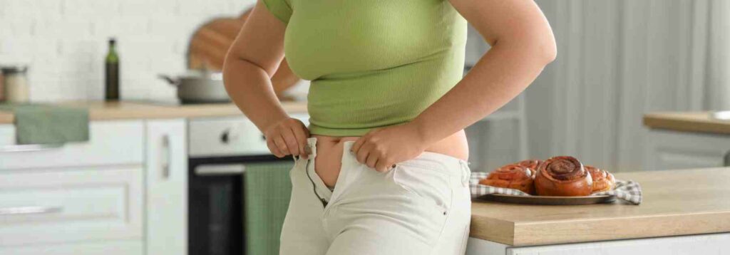 Woman struggling to do up her trousers before weight loss 