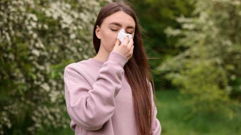Man blowing her nose outside from hay fever